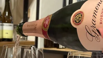 Wein wird aus einer Flasche in Gläser gegossen.