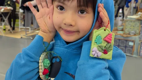 Child in blue hoodie showing handmade crafts.