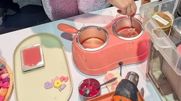 Person schmilzt Wachs mit einem pinken Wärmer.