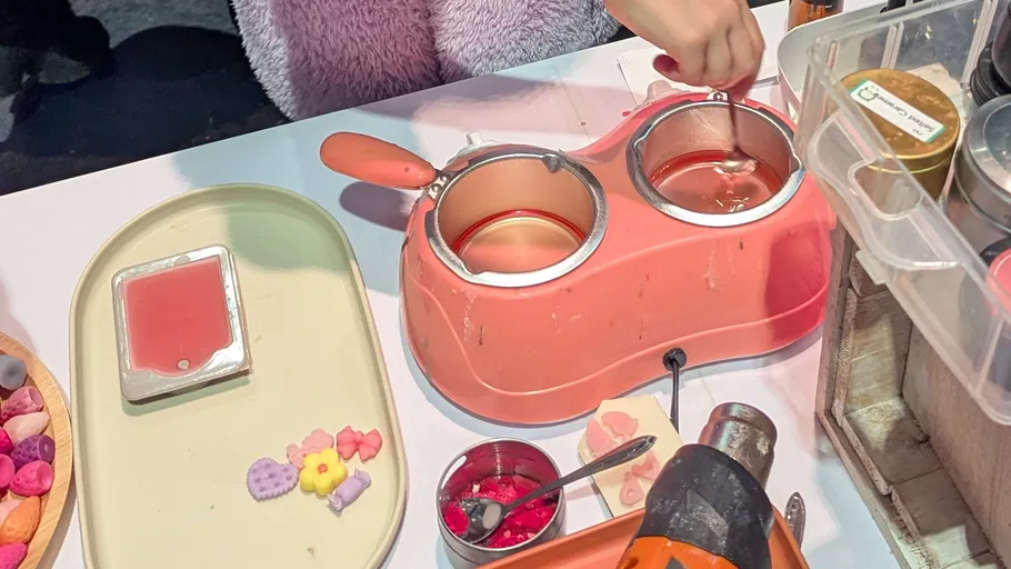 Person melting wax using a pink warmer.