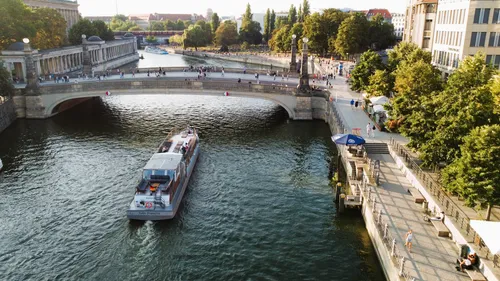 Boot fährt unter Stadtbrücke auf Fluss.