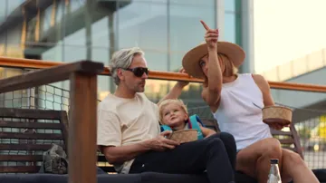Family eating and pointing outdoors scene.