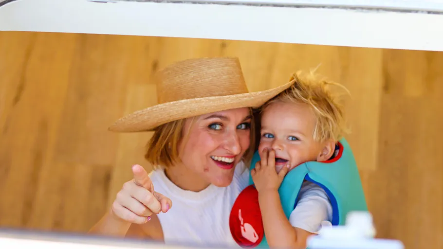 Woman with hat and child pointing inside a room.