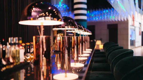 Stylish bar with glowing lamps, bottles visible.