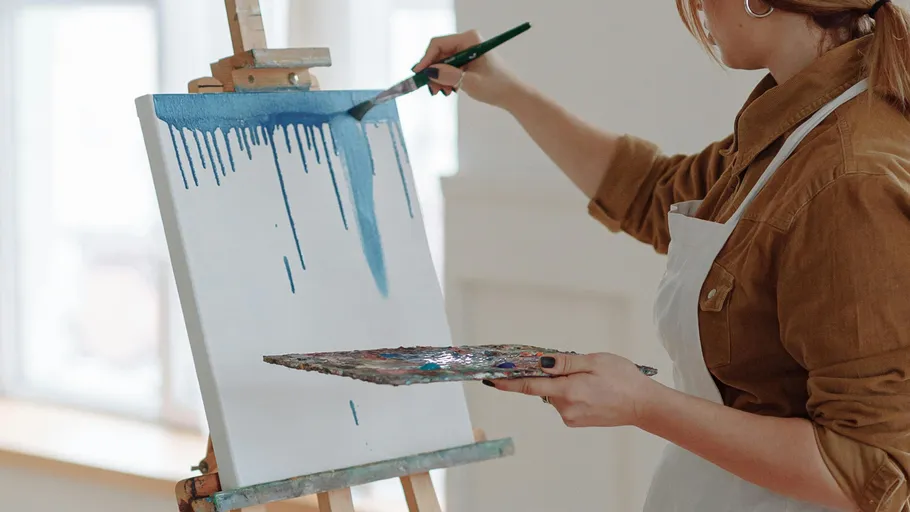 Person painting on easel in bright room.