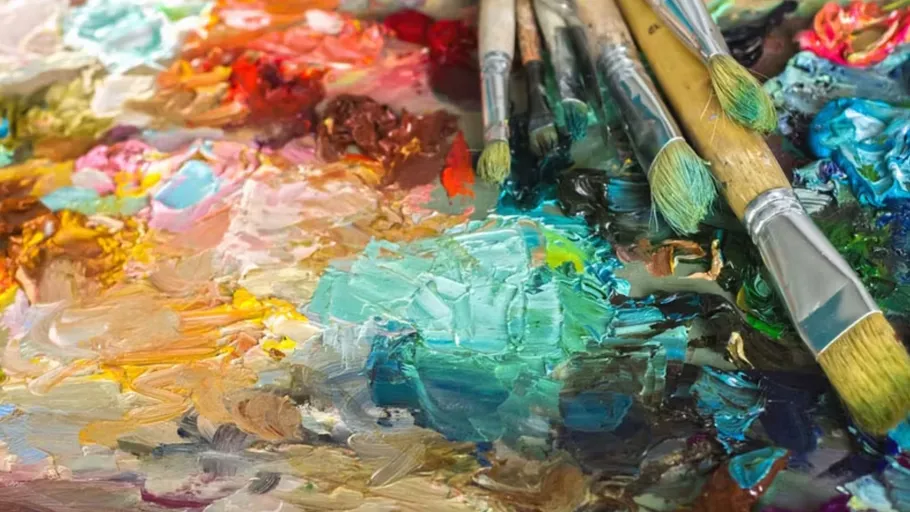 Paintbrushes on colorful mixed paint palette.
