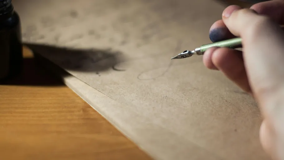 Hand writes with quill on paper, desk background.
