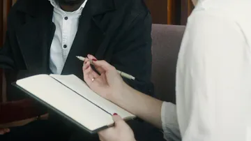 Person holding notebook in meeting room.