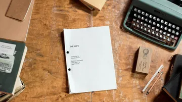Drehbuch auf Schreibtisch mit Schreibmaschine, Stiften und Büchern.