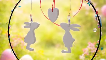 Two bunny cutouts hang with heart outdoors.
