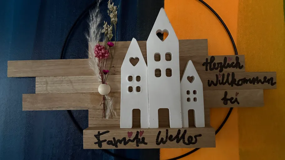 Holzschild mit dekorativen Häusern.