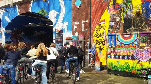 Group cycling by colorful street murals.