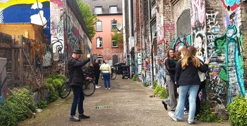 People in alley with graffiti-covered walls.