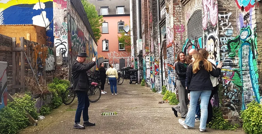 Menschen in Gasse mit Graffiti-Wänden.