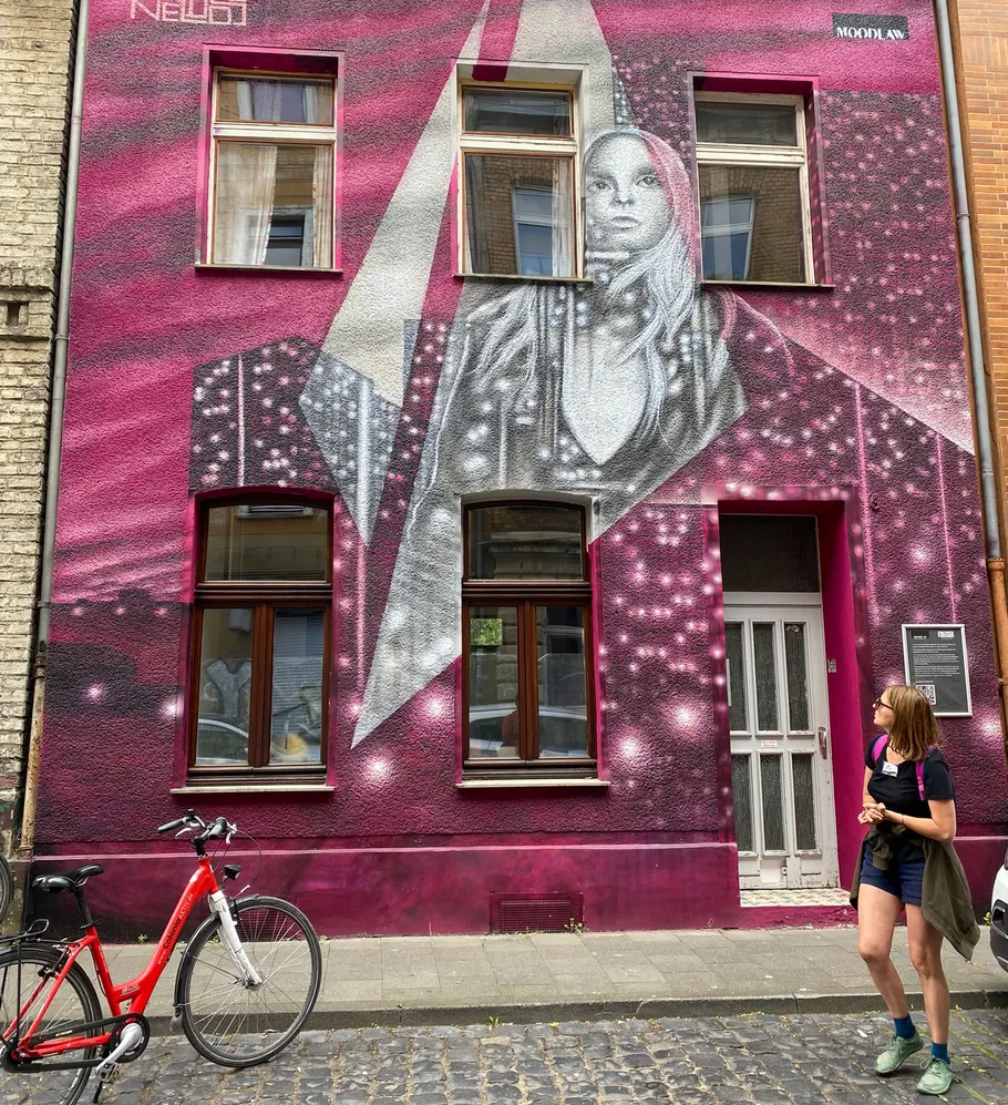Street art portrait on pink building wall.