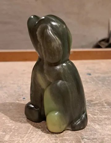 Grüne Steinskulptur eines Hasen auf Tisch.