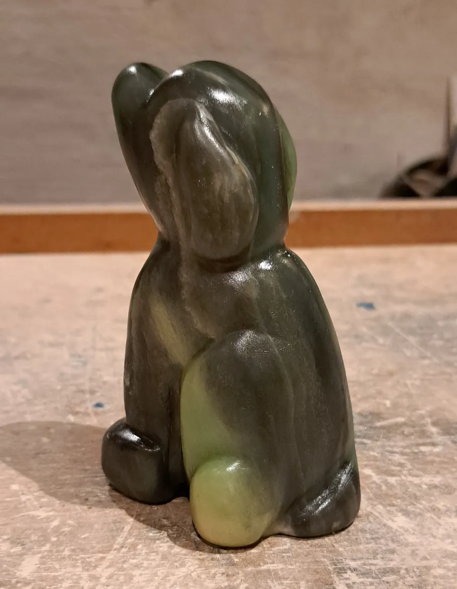 Grüne Steinskulptur eines Hasen auf Tisch.