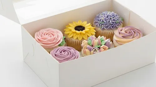 Blumen-Cupcakes in einer weißen Schachtel.