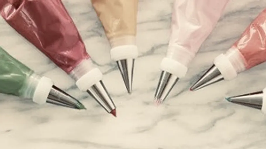 Colorful icing bags on a marble surface.