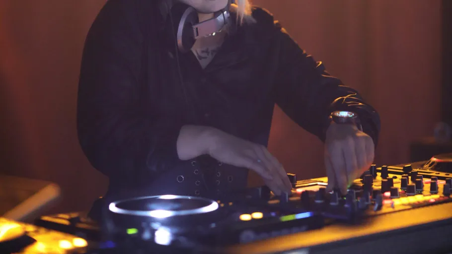 DJ using mixer in dimly lit space.