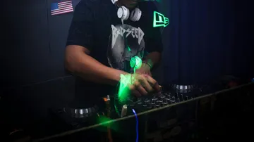 DJ mixing music in dark room.