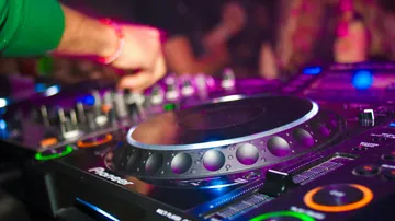 DJ mixing music on turntables, colorful lights.