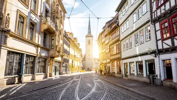 Street with tram tracks, church in background.