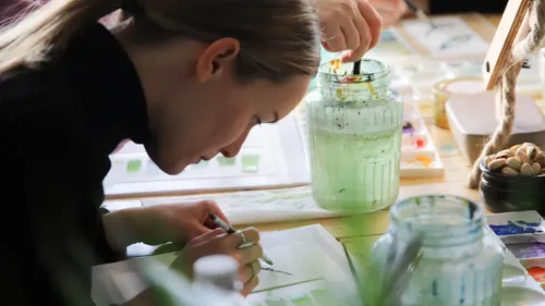 Person painting at a wooden table.