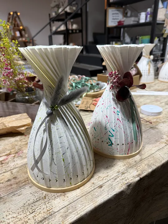 Papier-Vasen mit Dekorationen auf Holztisch.