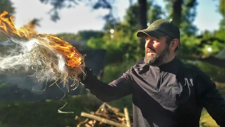 Man holding fiery object outdoors.