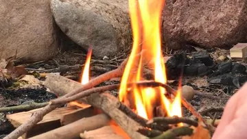 Small campfire burning surrounded by rocks.