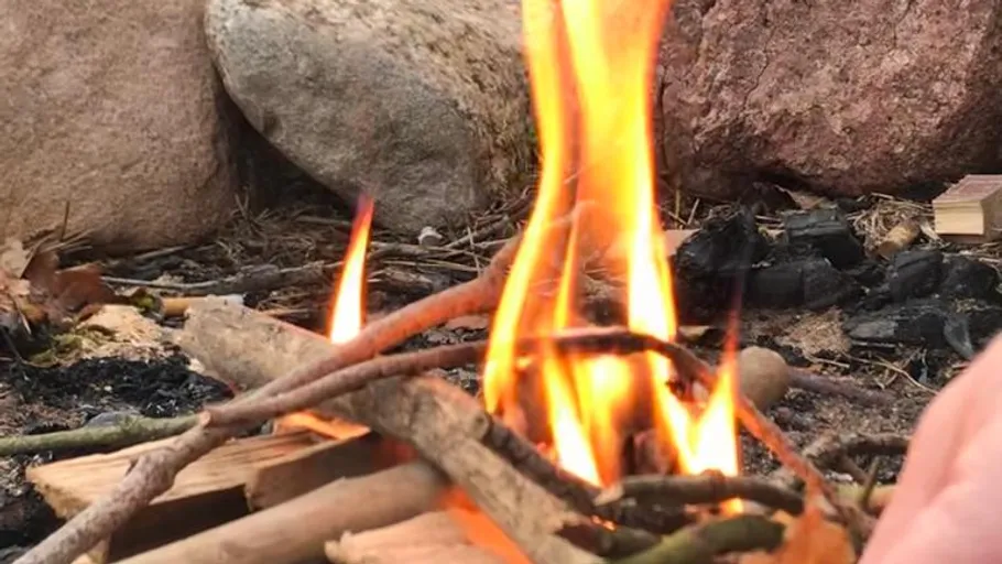 Small campfire burning surrounded by rocks.