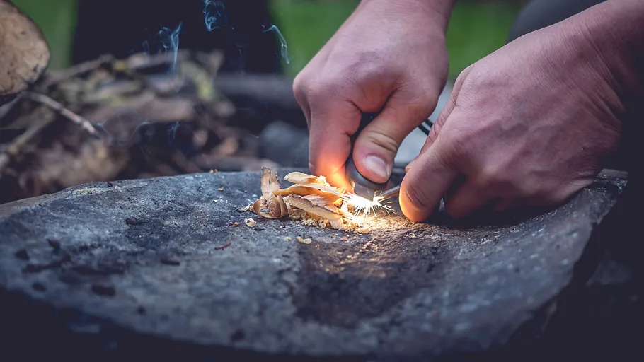 Hands striking flint to spark fire outdoors.