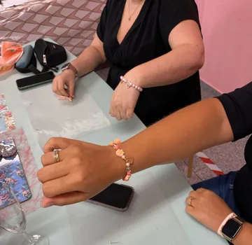 Two people showing bracelets in a workshop.