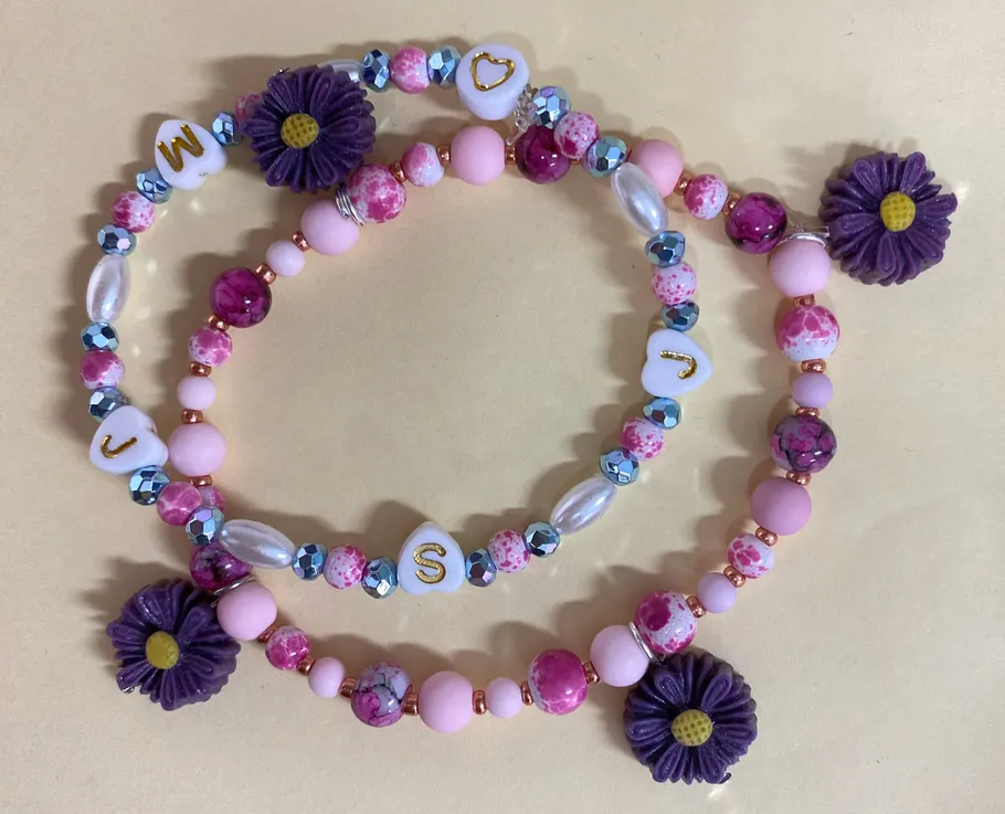Beaded bracelets with letters and purple flowers.