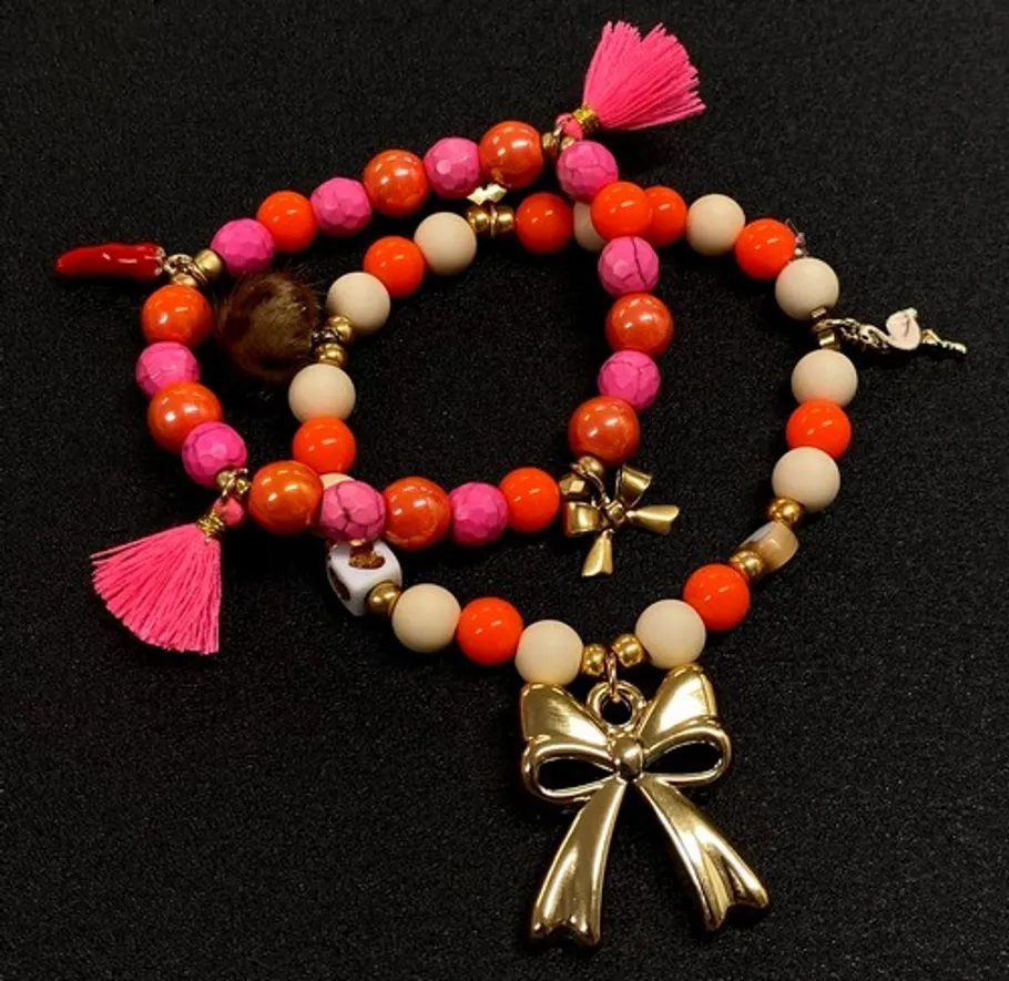 Bunte Perlenarmbänder mit goldenen Schleifenanhängern.