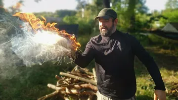 Man holding flaming object outdoors.