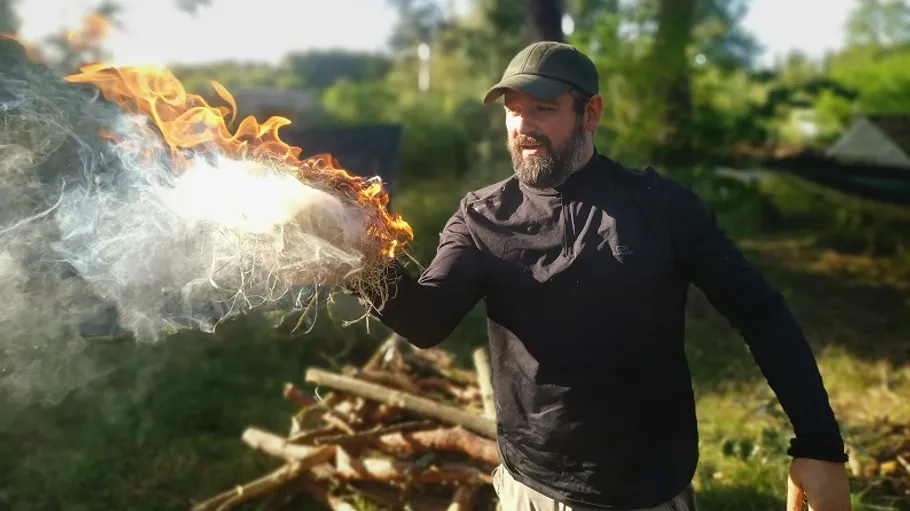 Man holding flaming object outdoors.