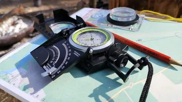 Compass and map on outdoor table.