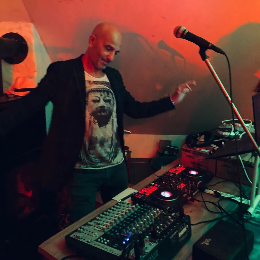 Person DJt mit Ausrüstung in schummrigem Raum.