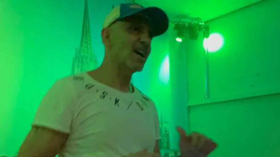 Person singing dynamically in green-lit room.