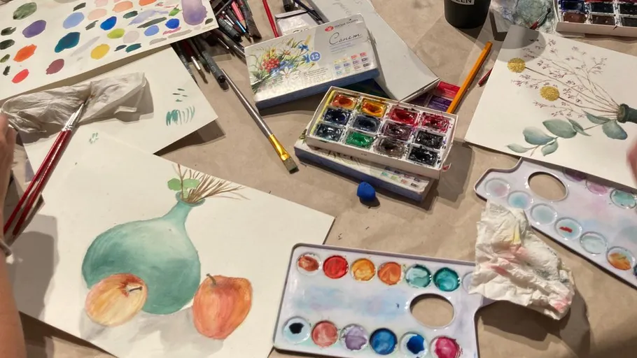 Aquarellmalerei mit Paletten auf Tisch.