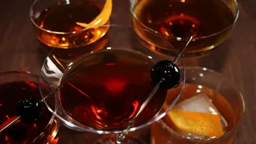 Cocktails with garnishes on wooden table.