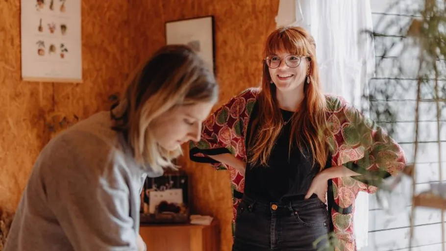 Zwei Frauen sprechen in einem gemütlichen Raum.