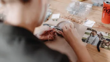 Person fertigt Schmuck auf Holztisch.