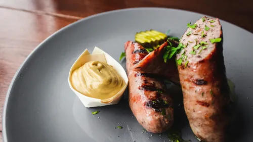 Grilled sausages with mustard on plate.
