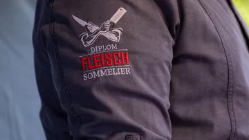 Jacket sleeve with embroidered words and knives.