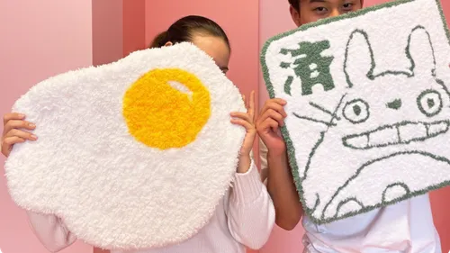 Two people holding colorful rug designs.