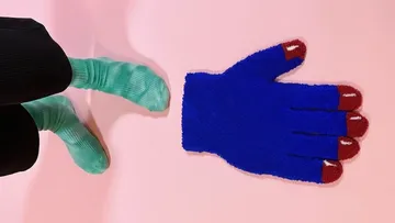 Riesenhandschuh auf Boden mit grünen Sockfüßen.