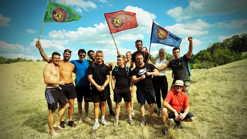Group holding flags outdoors on grassy hill.